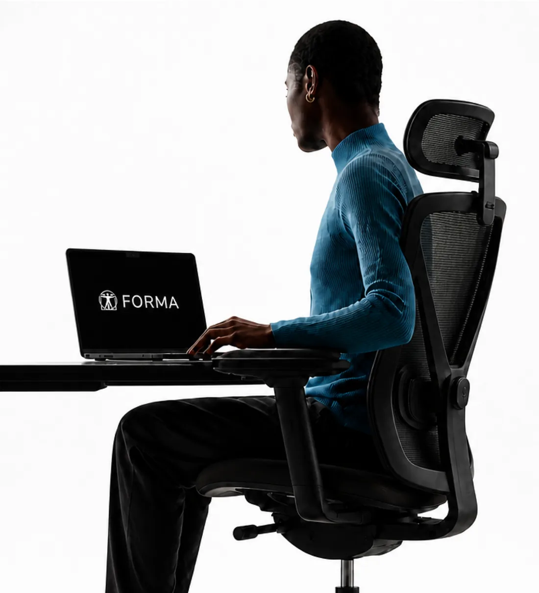 A person sitting at a desk and using Forma on a laptop